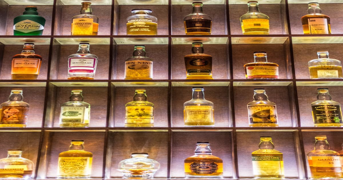 A backlit display wall of various whisky bottles